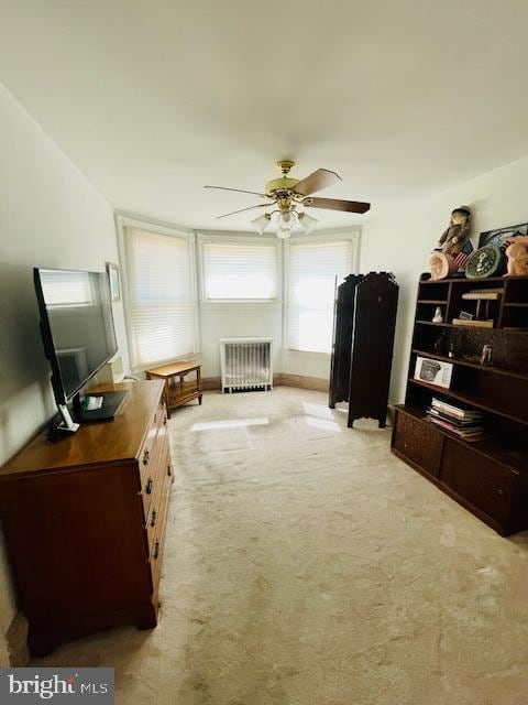 living area with ceiling fan, radiator heating unit, and light carpet