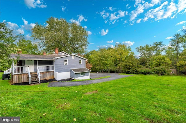 rear view of house featuring a lawn, covered porch, and a garage