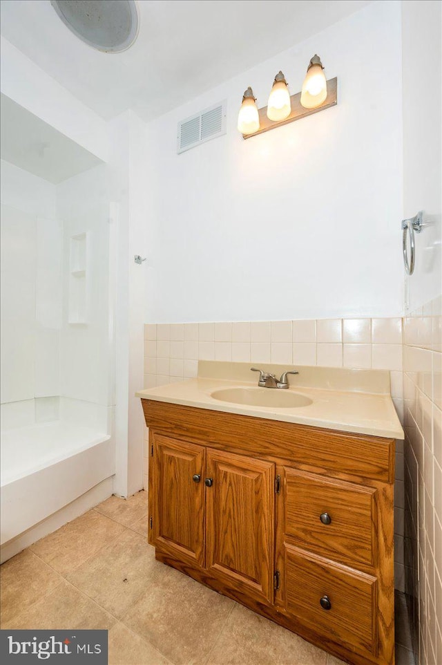 bathroom featuring vanity, tile walls, a shower, and tile patterned floors