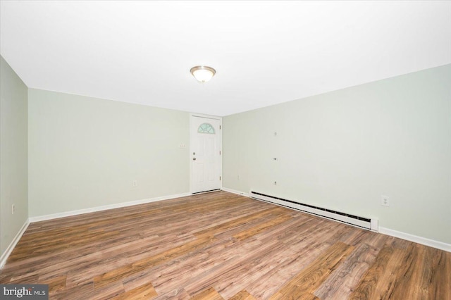 empty room featuring a baseboard heating unit and wood-type flooring