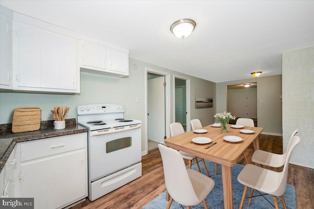 kitchen with dark hardwood / wood-style flooring, white range with electric stovetop, and white cabinets