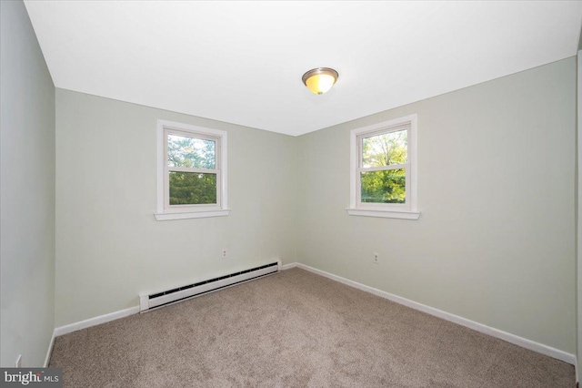 spare room with a baseboard heating unit, light colored carpet, and a healthy amount of sunlight