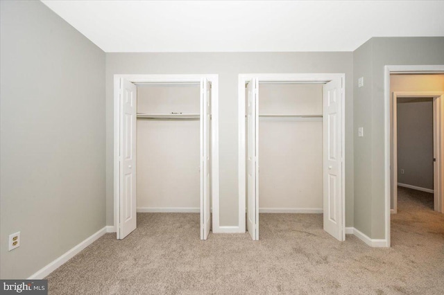 unfurnished bedroom with light carpet and two closets