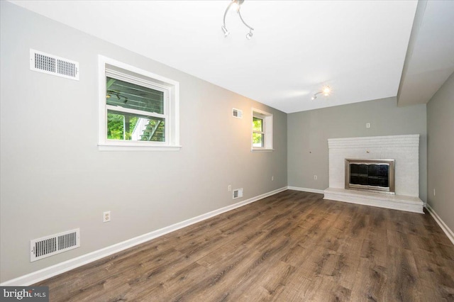 unfurnished living room with a brick fireplace and dark hardwood / wood-style flooring