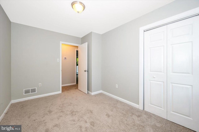 unfurnished bedroom featuring light colored carpet and a closet