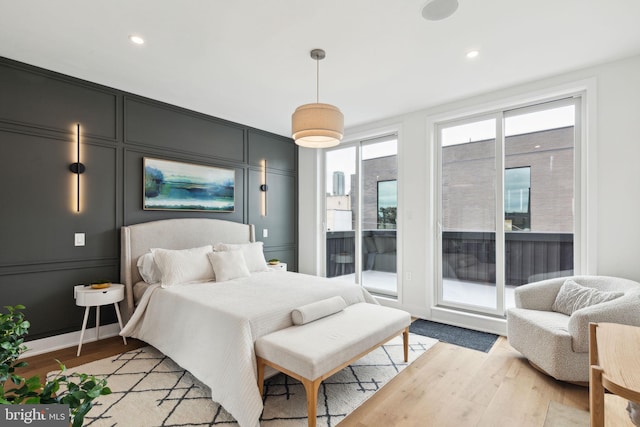 bedroom featuring access to exterior, light hardwood / wood-style floors, and multiple windows