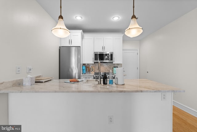 kitchen featuring pendant lighting, white cabinets, kitchen peninsula, and appliances with stainless steel finishes