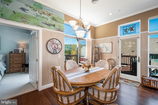 dining area with ornamental molding, a notable chandelier, and dark wood-type flooring