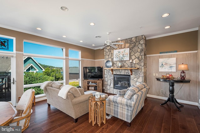 living room with a stone fireplace, ornamental molding, dark hardwood / wood-style floors, and ceiling fan