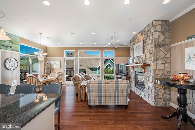 living room featuring crown molding, a stone fireplace, dark hardwood / wood-style flooring, and ceiling fan