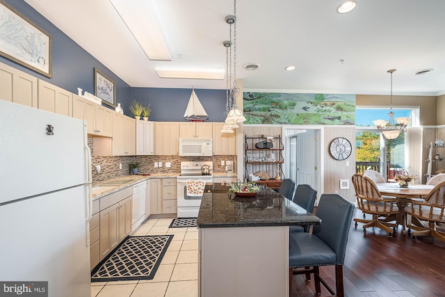 kitchen featuring a breakfast bar, hanging light fixtures, a kitchen island, light hardwood / wood-style flooring, and white appliances