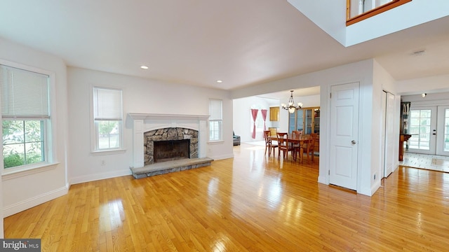 unfurnished living room featuring light hardwood / wood-style floors, plenty of natural light, and a stone fireplace