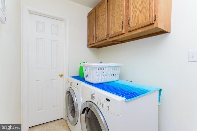 laundry area featuring cabinets, light tile patterned flooring, and washing machine and dryer