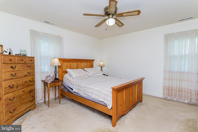 bedroom featuring light carpet, multiple windows, and ceiling fan