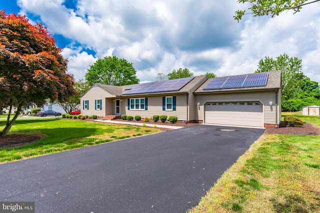 ranch-style home with a garage, a front lawn, and solar panels