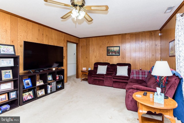 living room with ornamental molding, wood walls, ceiling fan, and light colored carpet