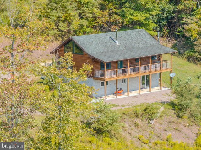 back of house with log siding, a shingled roof, and a patio