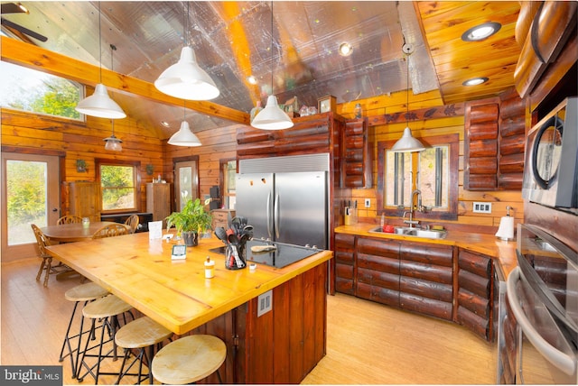 kitchen with stainless steel built in refrigerator, light hardwood / wood-style floors, hanging light fixtures, and sink