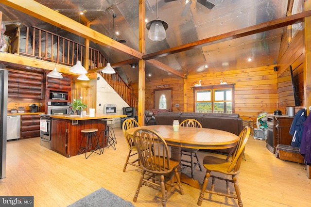 dining space featuring beamed ceiling, light wood-type flooring, wood walls, and high vaulted ceiling