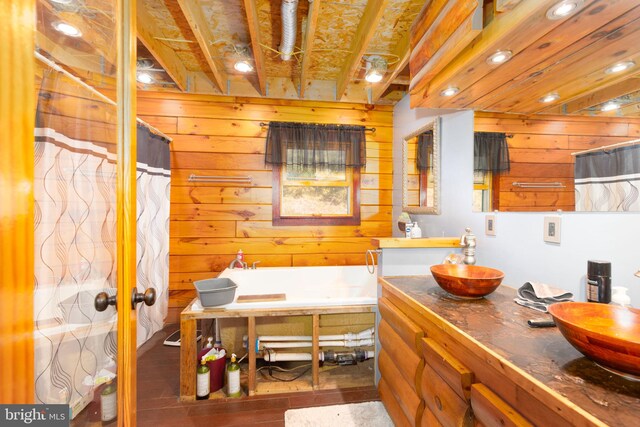 bathroom with wooden walls, a tub, hardwood / wood-style floors, and vanity