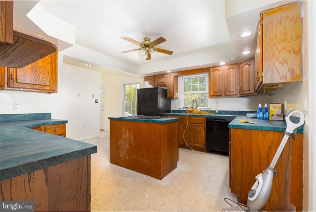 kitchen featuring black appliances, ceiling fan, a tray ceiling, and a kitchen island