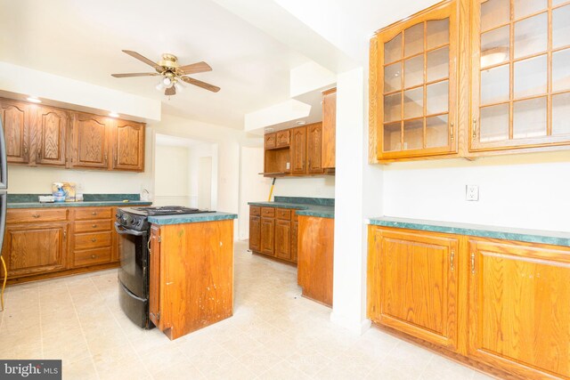 kitchen featuring ceiling fan, a center island, and black stove