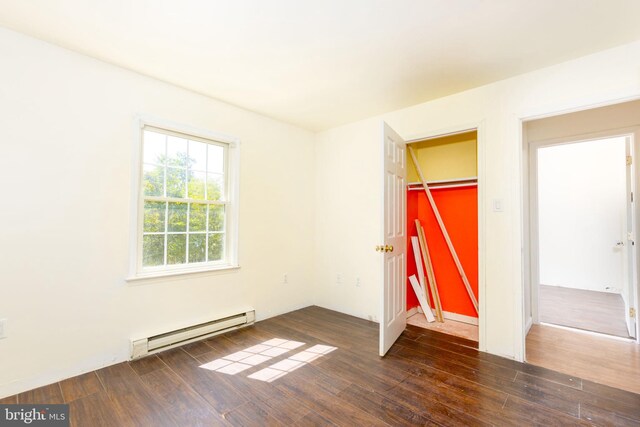 unfurnished bedroom with dark wood-type flooring, a baseboard heating unit, and a closet