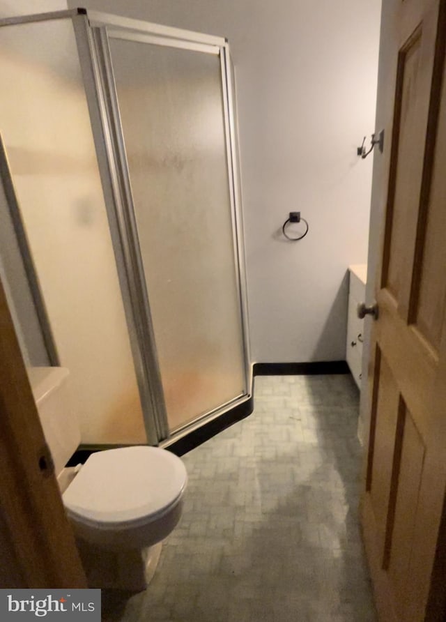 bathroom featuring toilet and an enclosed shower