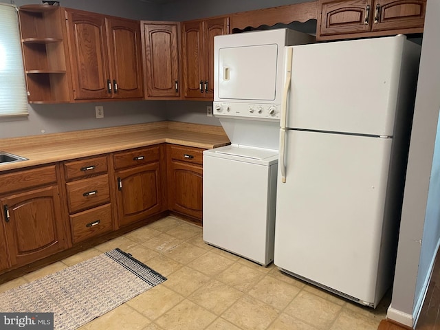 kitchen with sink, white fridge, and stacked washing maching and dryer