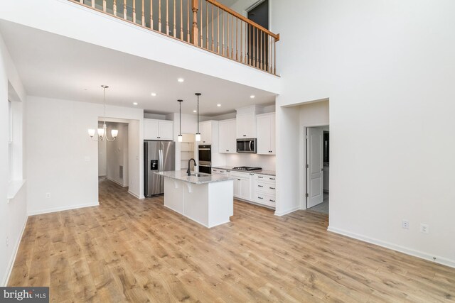 kitchen featuring appliances with stainless steel finishes, light hardwood / wood-style floors, a kitchen island with sink, and white cabinets