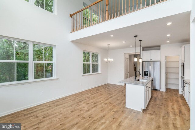 kitchen featuring white cabinetry, a center island with sink, appliances with stainless steel finishes, and plenty of natural light