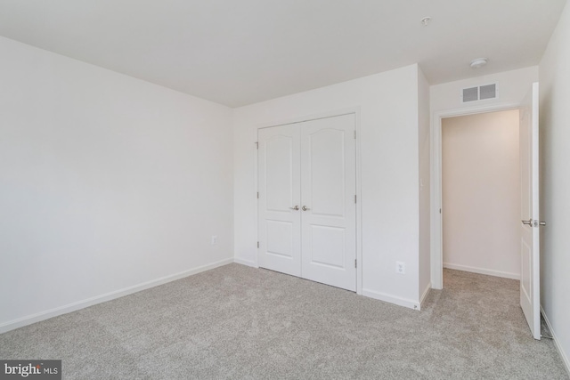 unfurnished bedroom featuring a closet and light colored carpet