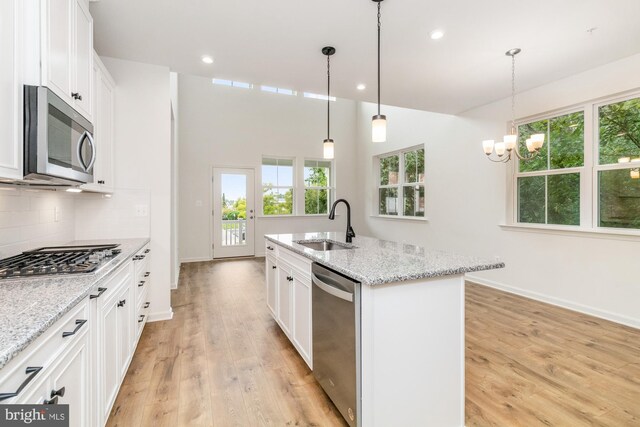 kitchen featuring light stone counters, sink, a center island with sink, white cabinetry, and stainless steel appliances