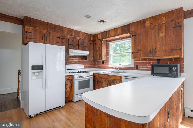 kitchen with decorative backsplash, white appliances, kitchen peninsula, light wood-type flooring, and sink