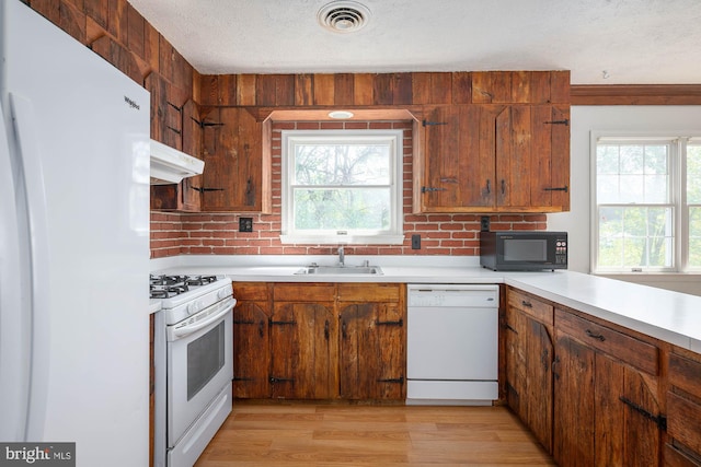 kitchen featuring decorative backsplash, white appliances, a textured ceiling, light hardwood / wood-style flooring, and sink