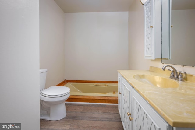 bathroom with vanity, toilet, hardwood / wood-style floors, and a washtub