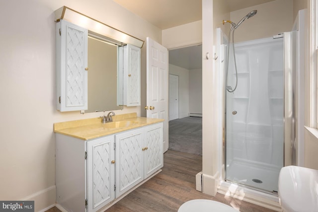 bathroom featuring vanity, baseboard heating, walk in shower, hardwood / wood-style floors, and toilet