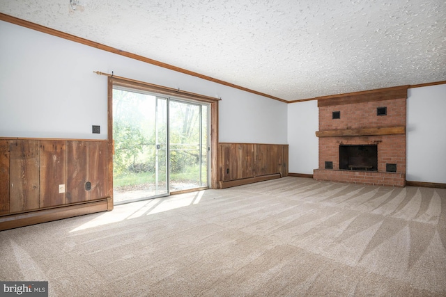 unfurnished living room featuring a brick fireplace, a textured ceiling, wood walls, and light carpet