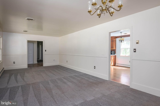 spare room with a notable chandelier, dark colored carpet, and baseboard heating