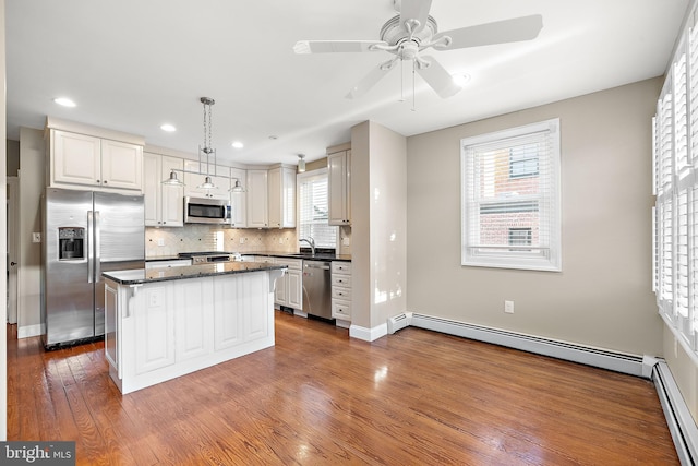 kitchen featuring baseboard heating, a center island, decorative light fixtures, and appliances with stainless steel finishes