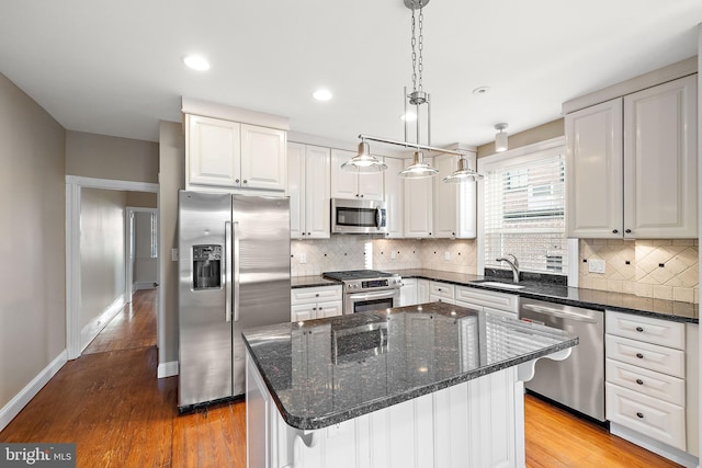 kitchen featuring white cabinets, decorative light fixtures, a kitchen island, and stainless steel appliances