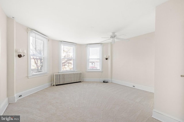 spare room with ceiling fan, radiator heating unit, and light colored carpet