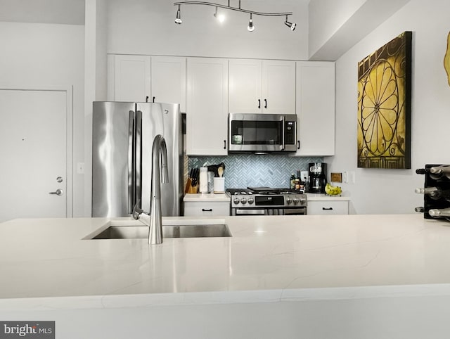 kitchen with light stone counters, stainless steel appliances, sink, and white cabinetry