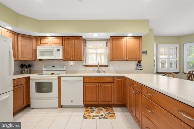 kitchen featuring white appliances, light tile patterned flooring, sink, and kitchen peninsula