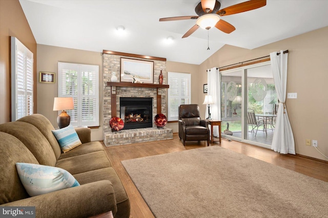 living room featuring ceiling fan, a fireplace, lofted ceiling, and a healthy amount of sunlight