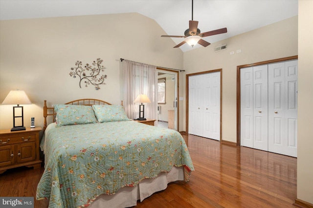 bedroom with lofted ceiling, two closets, hardwood / wood-style floors, and ceiling fan