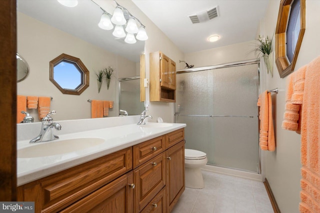 bathroom featuring vanity, toilet, a shower with door, and tile patterned floors