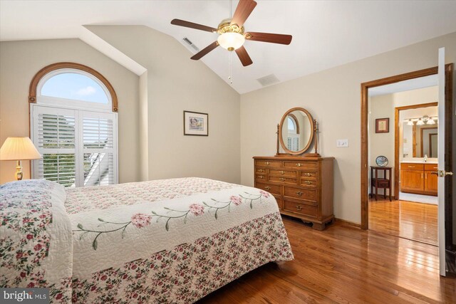 bedroom with sink, vaulted ceiling, ensuite bath, hardwood / wood-style floors, and ceiling fan