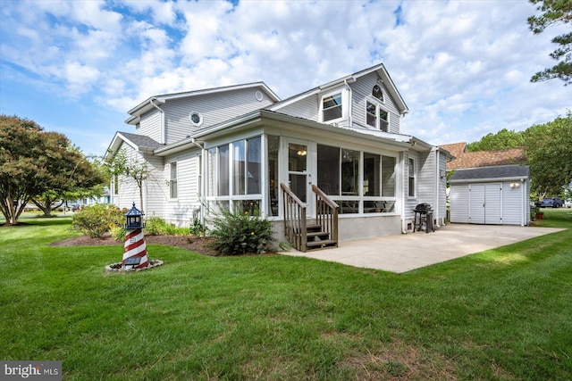 back of house with a lawn, an outbuilding, a garage, and a sunroom