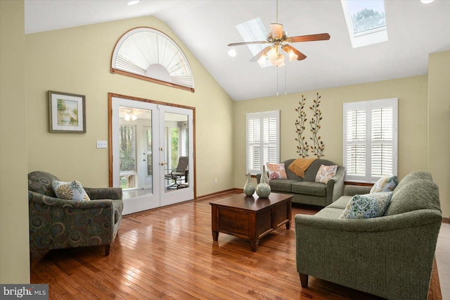 living room with a skylight, ceiling fan, hardwood / wood-style flooring, and plenty of natural light